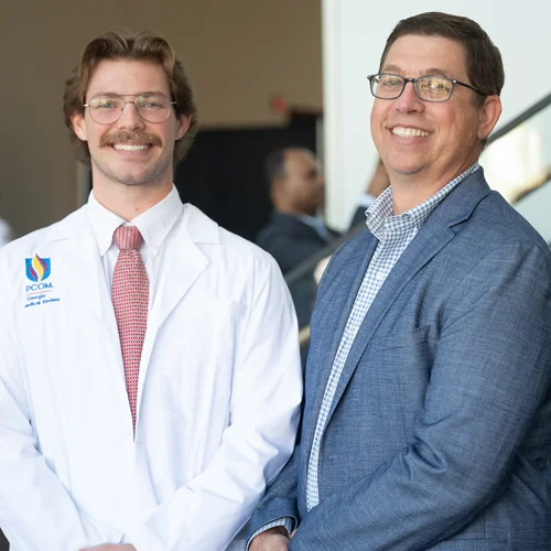John “Jackson” Norris (DO ‘29) wearing a white coat and his father, J Norris, DO’ 17