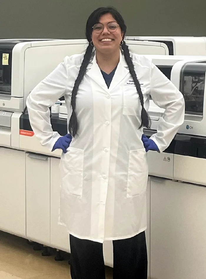PCOM Georgia MLS student Noemi Gomez Vaca (MS/MLS '26) smiles while wearing a white lab coat in a laboratory