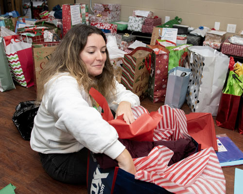 Female student wraps presents while sitting on floor