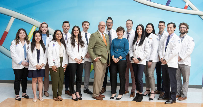 Members of the PCOM Georgia DO program pose together in front of blue wall