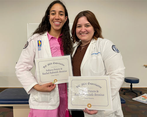 Sahara Peters (DO ’24) and classmate holding paper certificates recognizing them as "Class Parents"