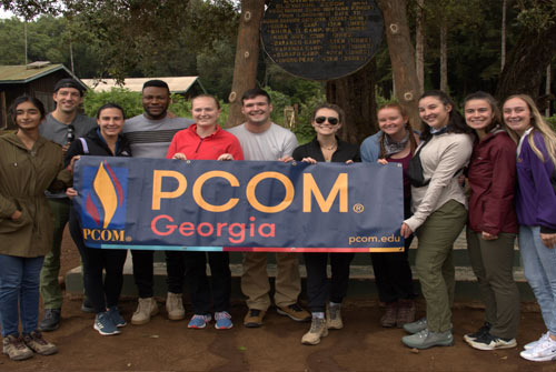 PCOM Georgia medical students pose with PCOM banner