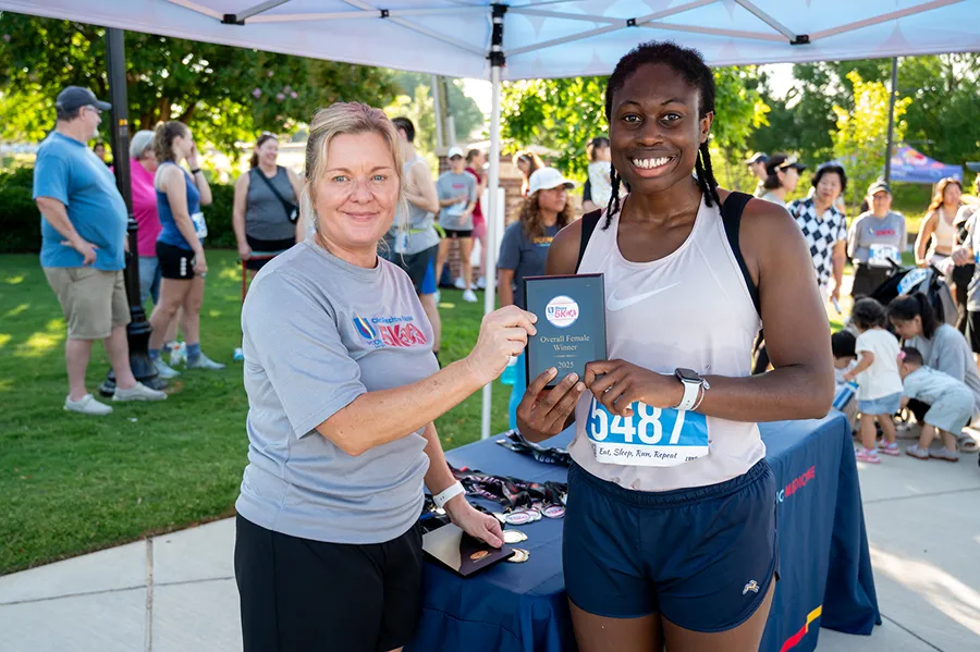 PCOM Georgia staff member Kim Lucier presents an award to the women’s overall 5k winner, Mo Olocha.