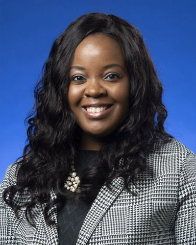 Professional headshot photograph of Kala Hurst (DO '22) smiling in front of a blue background