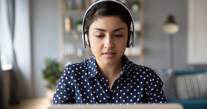 Medical student wears headphones and listens to a webinar on racial injustice on her laptop.