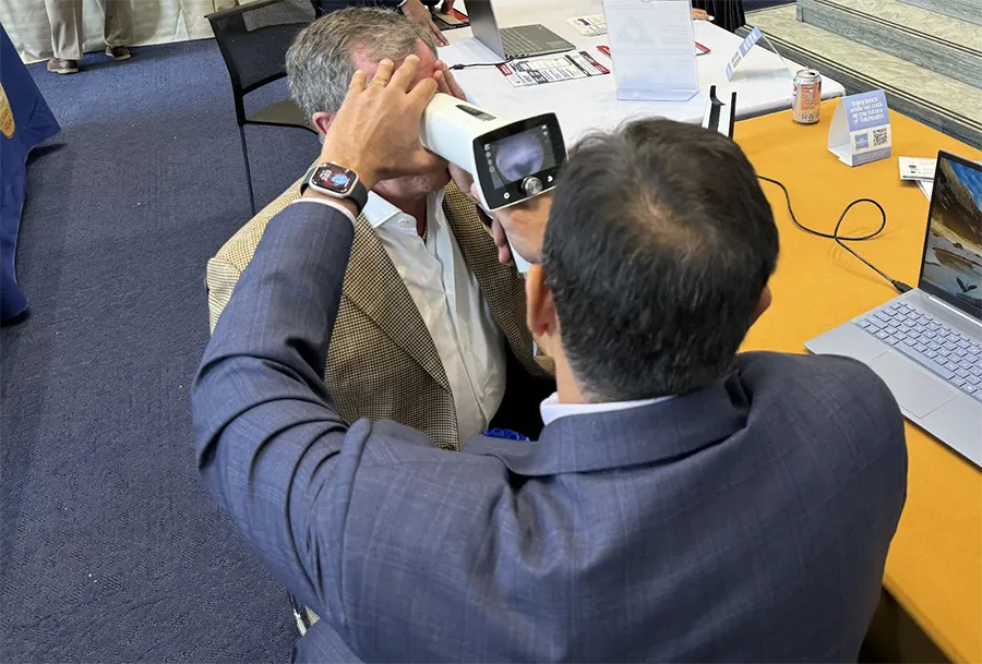Saad Rahman (DO '28) uses a retinal scanner tool to demo 360 Intelligent Diagnostics' AI-assisted retinal screening tool