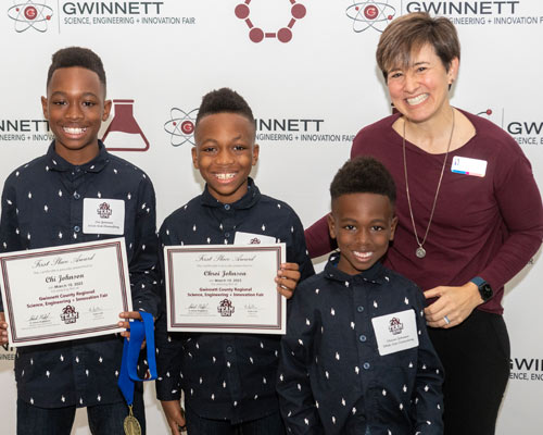 Dr. Andrea Mann with 3 middle school science fair attendees
