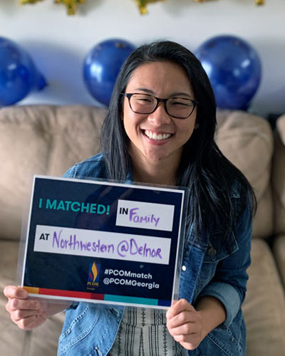 Smiling medical student holds sign announcing she has matched to a residency program.
