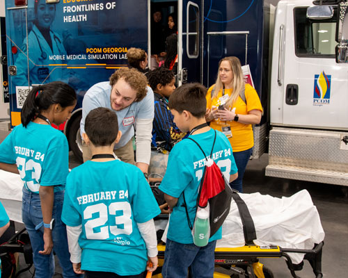 PCOM student talks to students at Simbulance exhibit