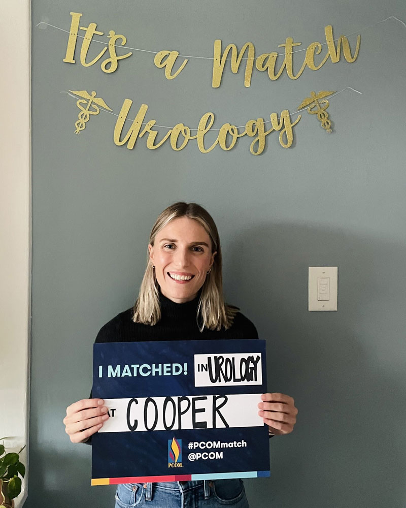 Smiling medical student holds sign announcing she has matched to a residency program.