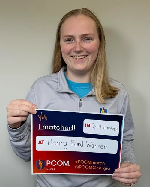 DO student and soon-to-be graduate Jessica Meredith (DO '26) holds up her sign matching in ophthalmology at Henry Ford Warren Hospital in Warren, Michigan during a Match Day celebration