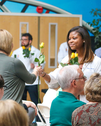 PCOM Georgia medical student hands a flower to a donor's family member