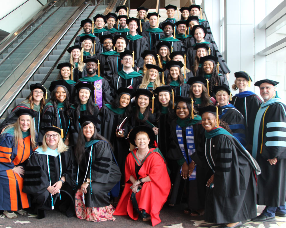 Members of the PCOM Georgia 2023 graduating class pose on a staircase in full regalia