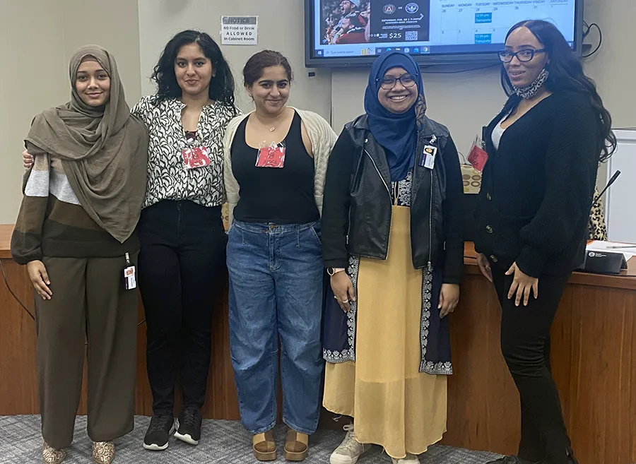 PCOM Georgia students and interns smile in front of a presentation desk at the DeKalb Regional Science and Engineering Fair
