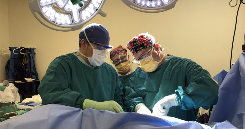 A PCOM Georgia medical student watches a physician perform a procedure in a surgery room.