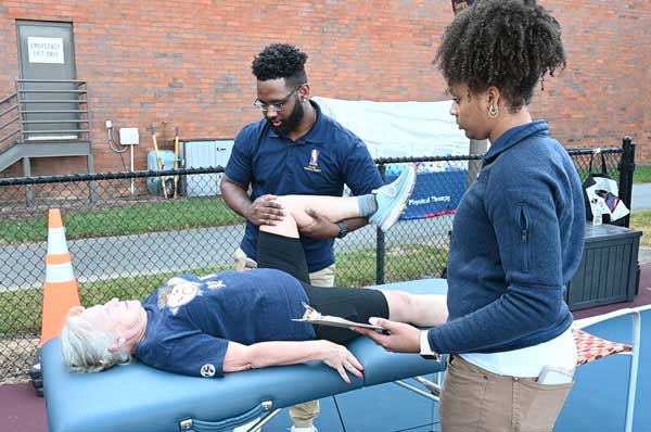 Two PT students work with a female patient on the pickleball court.