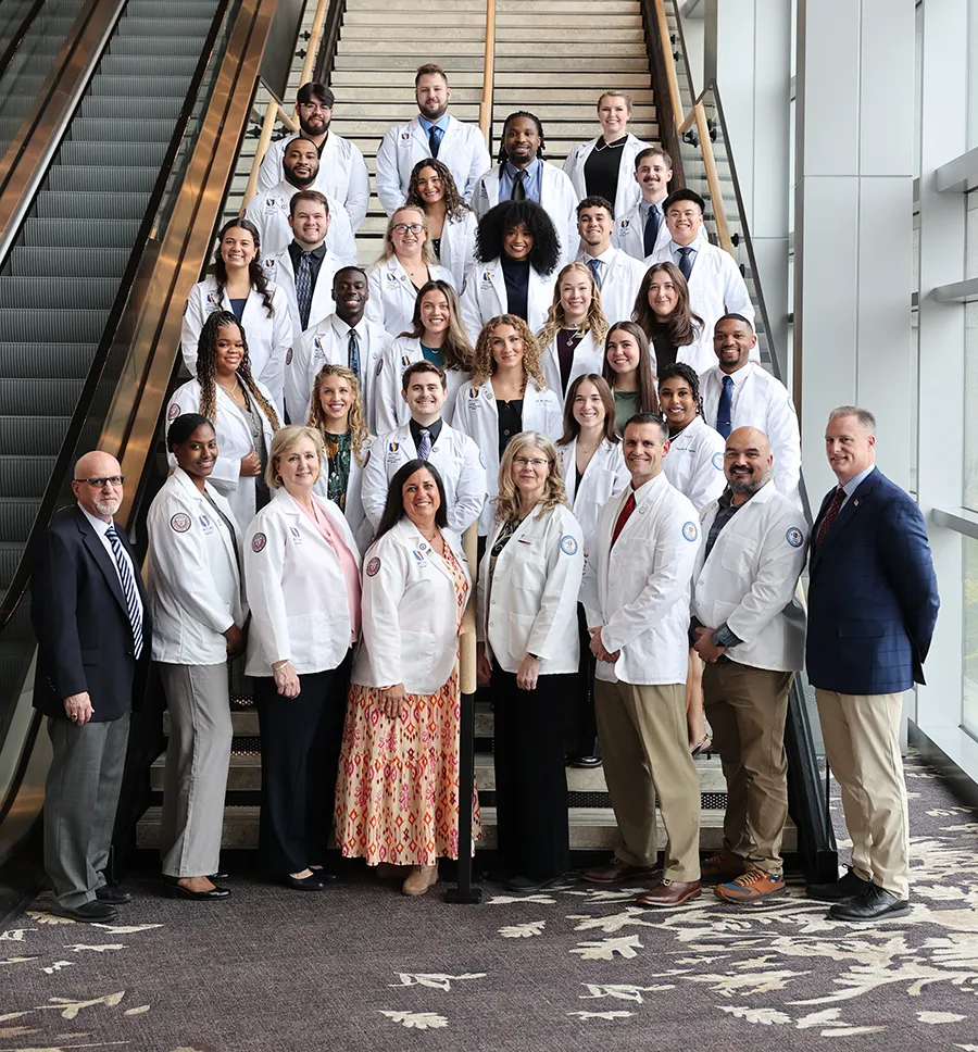 Group shot of PCOM Georgia's Doctor of Physical Therapy Class of 2027 students and faculty smiling on a staircase after the 2025 white coat ceremony