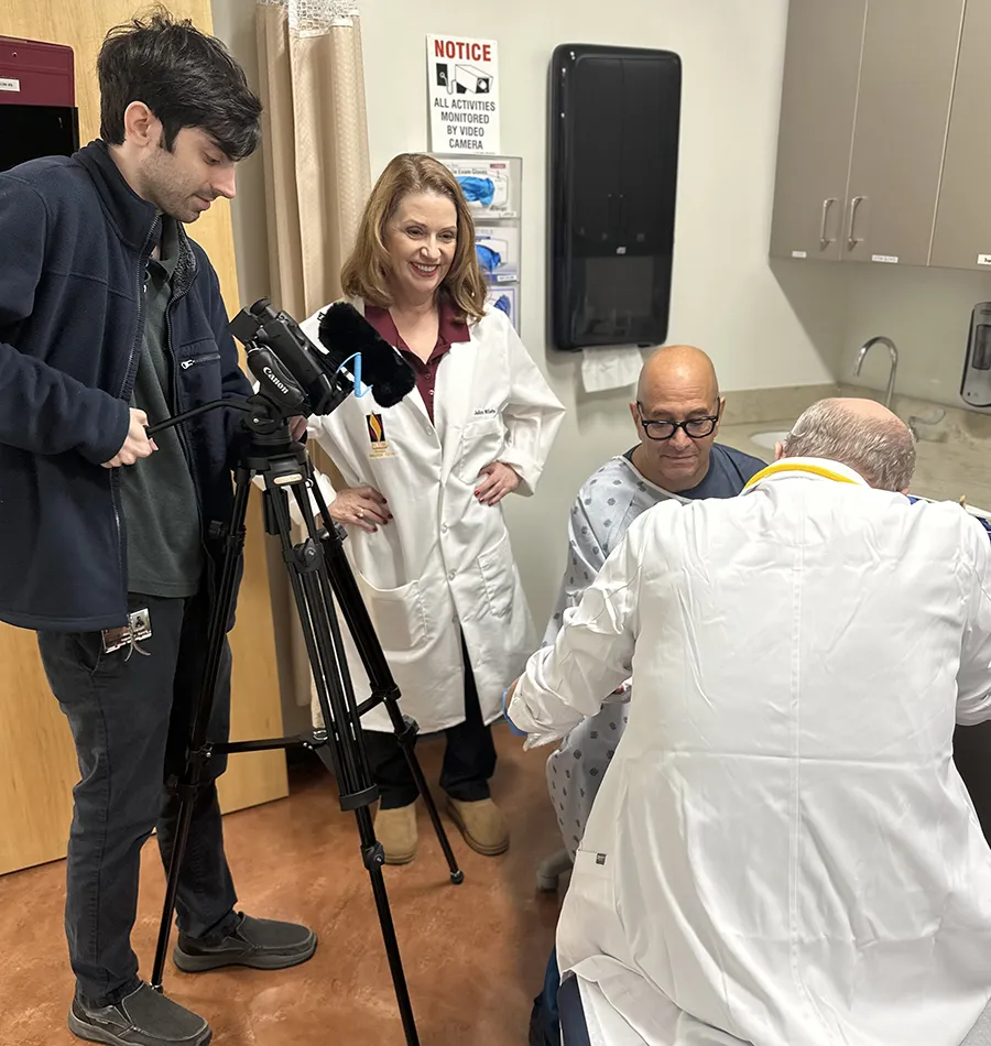 PCOM Georgia's JoAnn Willette smiles while working with other clinical simulation staff to film a training session with a standardized patient