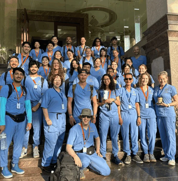 A group of medical students wearing blue medical scrubs pose on a stairway