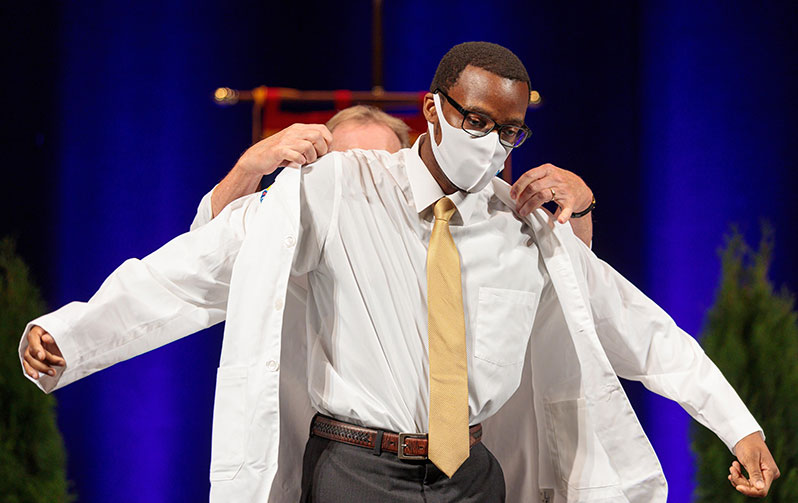 A PCOM Georgia DO student dons his white coat during the 2021 White Coat Ceremony