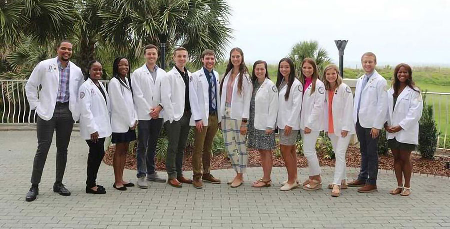 PCOM Georgia pharmacy students pose in their physician white coats outside of the GPhA convention