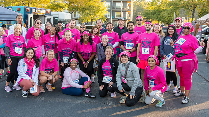 A large group of PCOM Georgia students and staff smile in pink shirts at the Paint Gwinnett Pink event