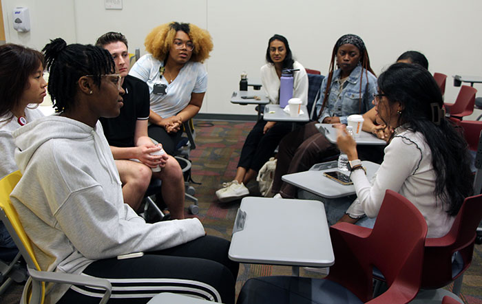 A large group of medical students talk in a classroom during a medical Spanish course