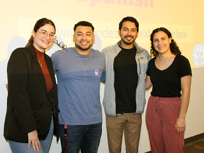 Four PCOM osteopathic medicine students pose and smile in a classroom