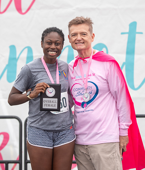 A PCOM Georgia student and staff member smile with awards from the 5K run