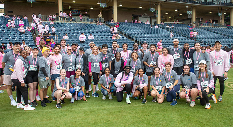 Large group of PCOM Georgia students, faculty, and staff smiling in pink attire