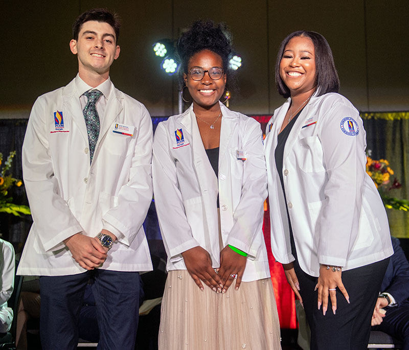 PCOM Georgia Pharmacy students smile as they don their white coats on stage