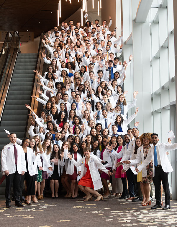 Large group shot of PCOM medical students and faculty smiling and waving in the Gas South District building