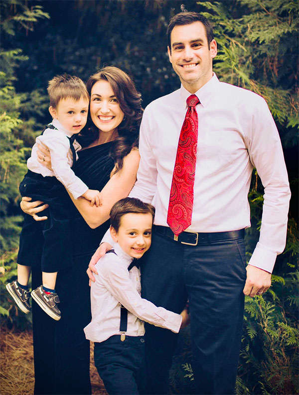 Joy Zarandy and her husband and two sons smile in a family portrait outside
