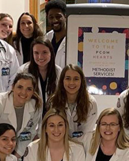 Students of the PCOM Hearts Club smile in a health clinic lobby.