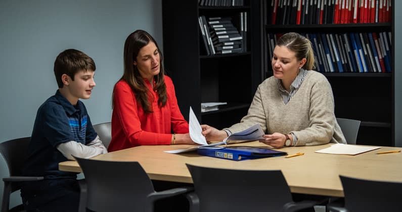 A school psychologist works with a parent and child at a table.