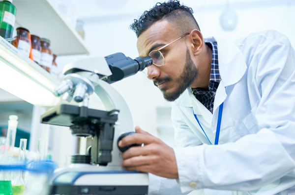 Medical student using microscope in research lab
