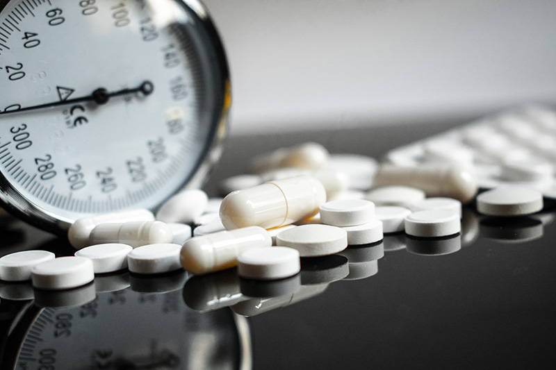 Stethoscope and various blood pressure medication pills on a doctor's table