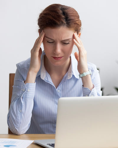 Clinician sits at laptop computer looking stressed