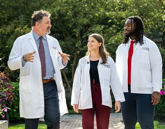 PCOM DO students smile and walk with a faculty member at PCOM's Philadelphia campus