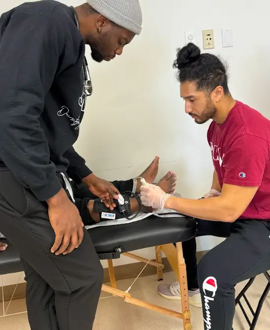 PCOM med students conduct blood pressure screenings on a patient during a health fair