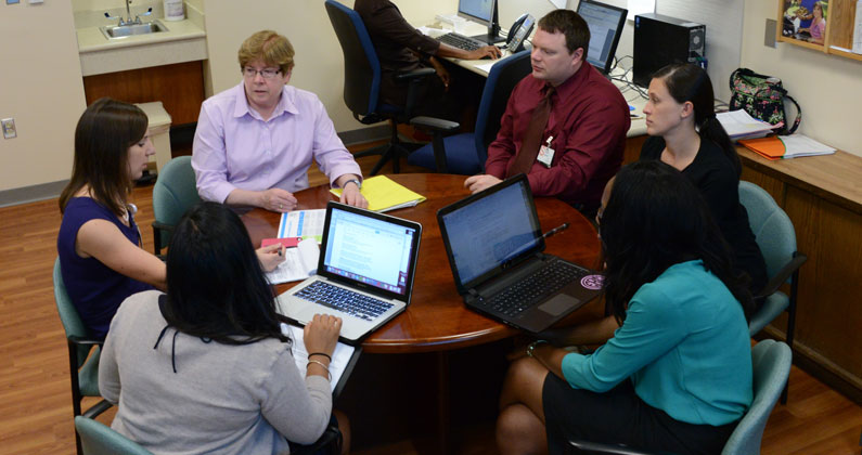 Students and staff sit around a round table having a group discussion