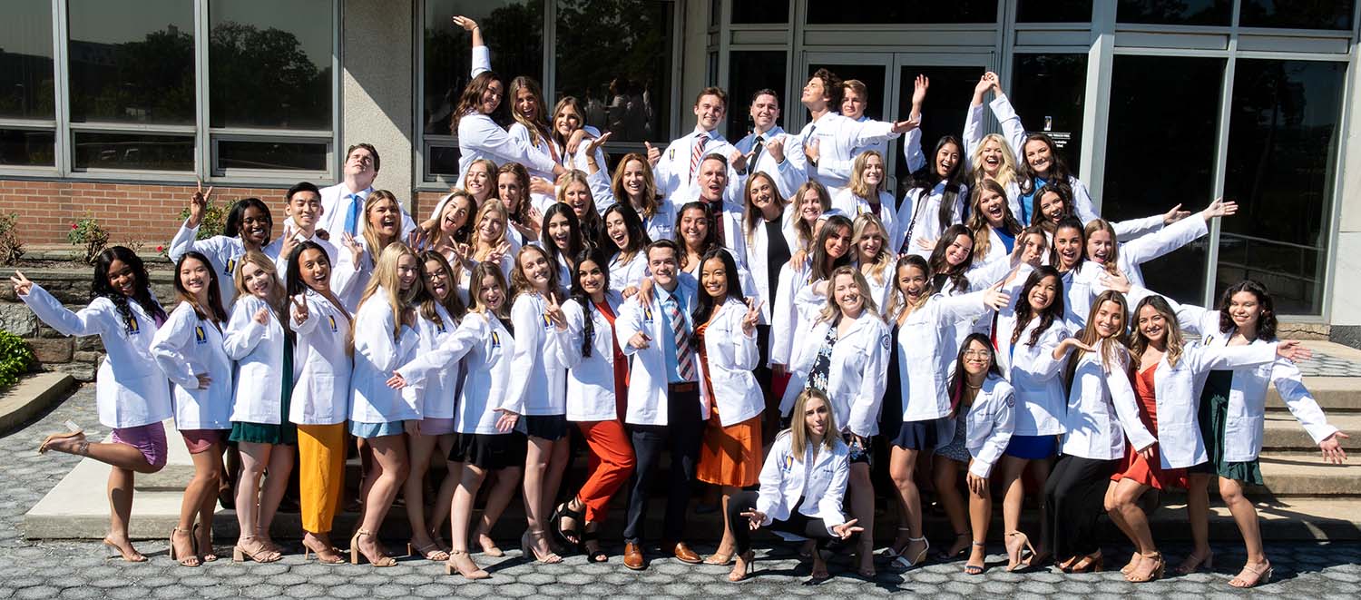PCOM's PA Studies Class of 2024 laugh and pose in their white coats at the Philadelphia campus after the PA white coat ceremony