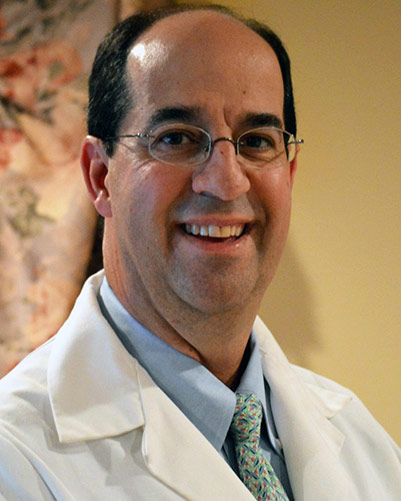 PCOM professor and POFPS board member George N. Spyropoulos, DO '92, smiles and wears white physician coat