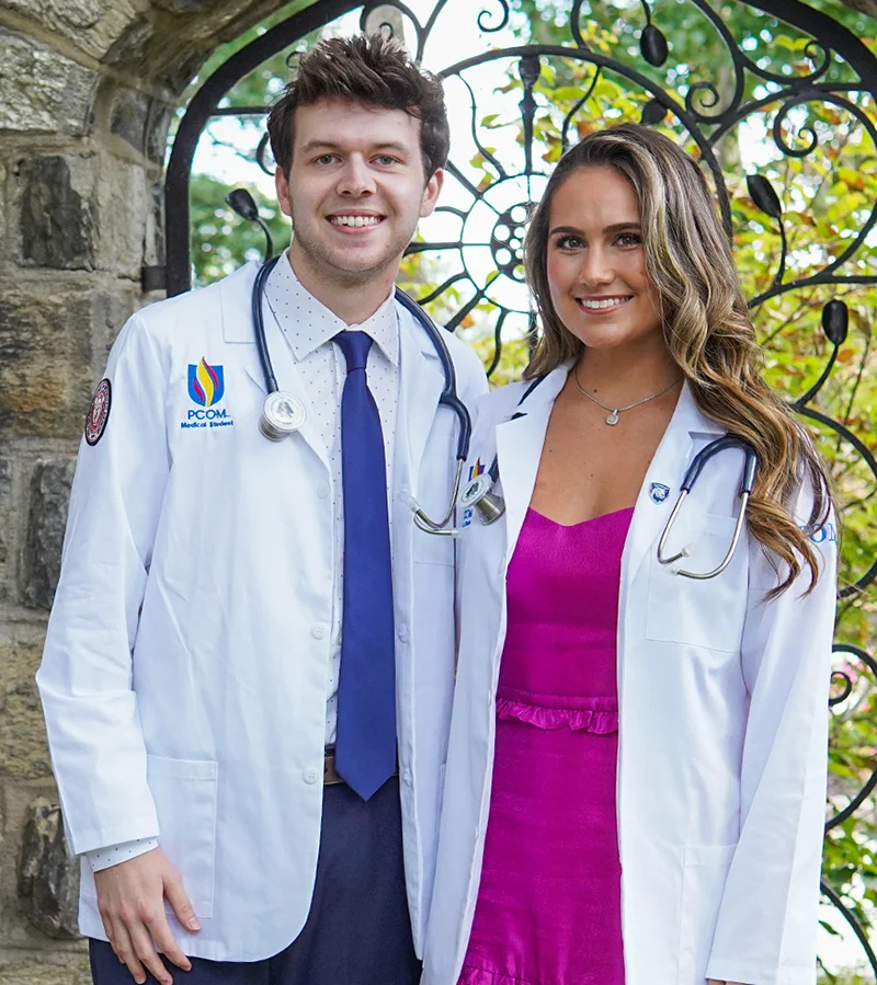 PCOM DO students and pediatric cancer survivors Dawson Nailor and Ellie Koerner smile in their physician wide coats