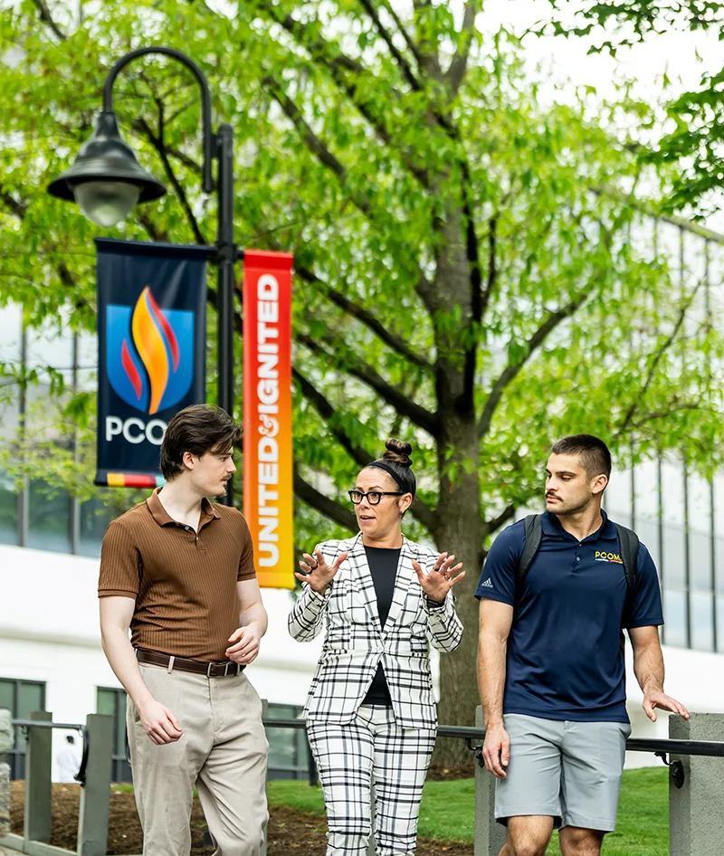 Dr. Missy Terlecki walking and talking with students on a pathway at PCOM's Philadelphia campus