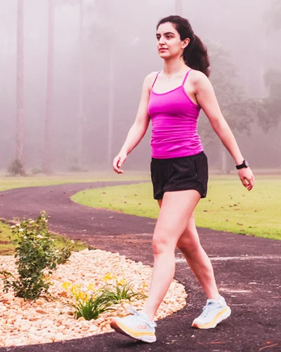 Young woman walks along walking path in morning fog