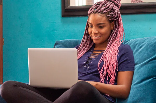 A girl sits on a couch with a computer in her lap