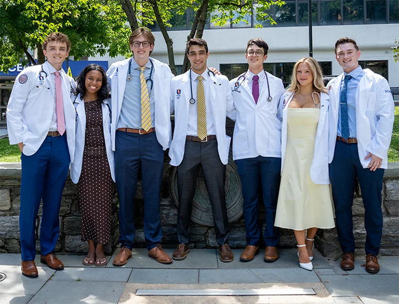 A group of PCOM medical students smile in their new white coats after the white coat ceremony
