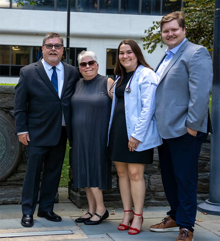 PCOM DO student Avery Periard and her family smiling on the PCOM Philadelphia grounds after the 2026 white coat ceremony