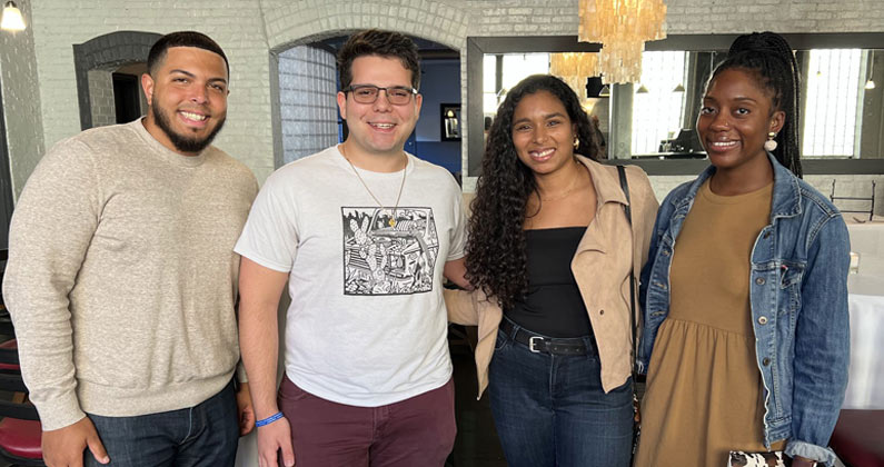 PCOM students pose side-by-side in a restaurant with exposed brick walls and modern light fixtures